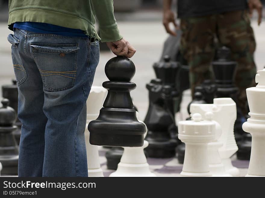 A man moves his Giant Pawn in a game of chess on the street. A man moves his Giant Pawn in a game of chess on the street