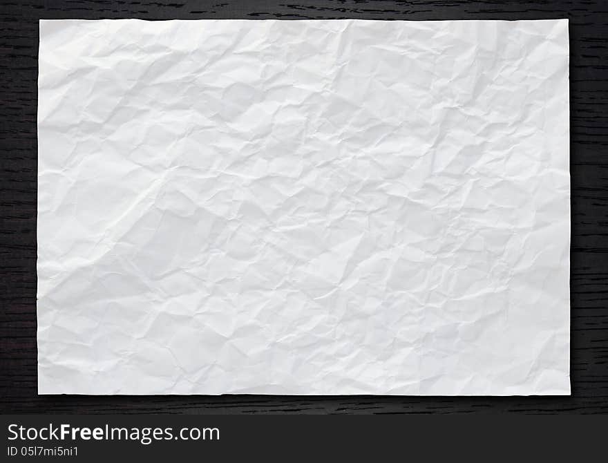 White crumpled paper on dark wood