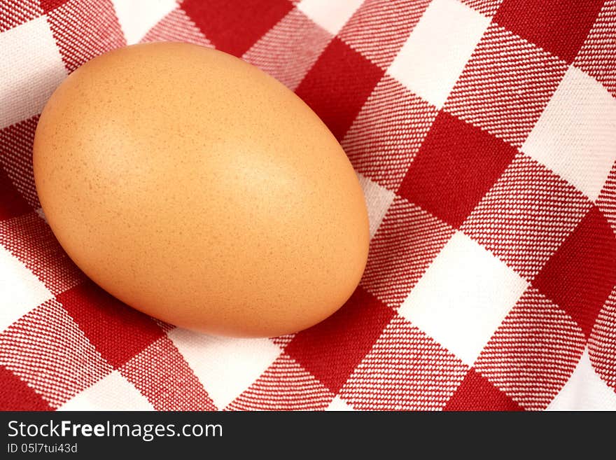 Single brown egg on a tablecloth. Horizontal position.