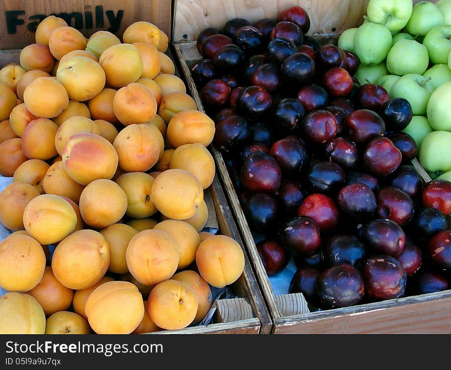 Assorted summer fruits displayed in wooden boxes