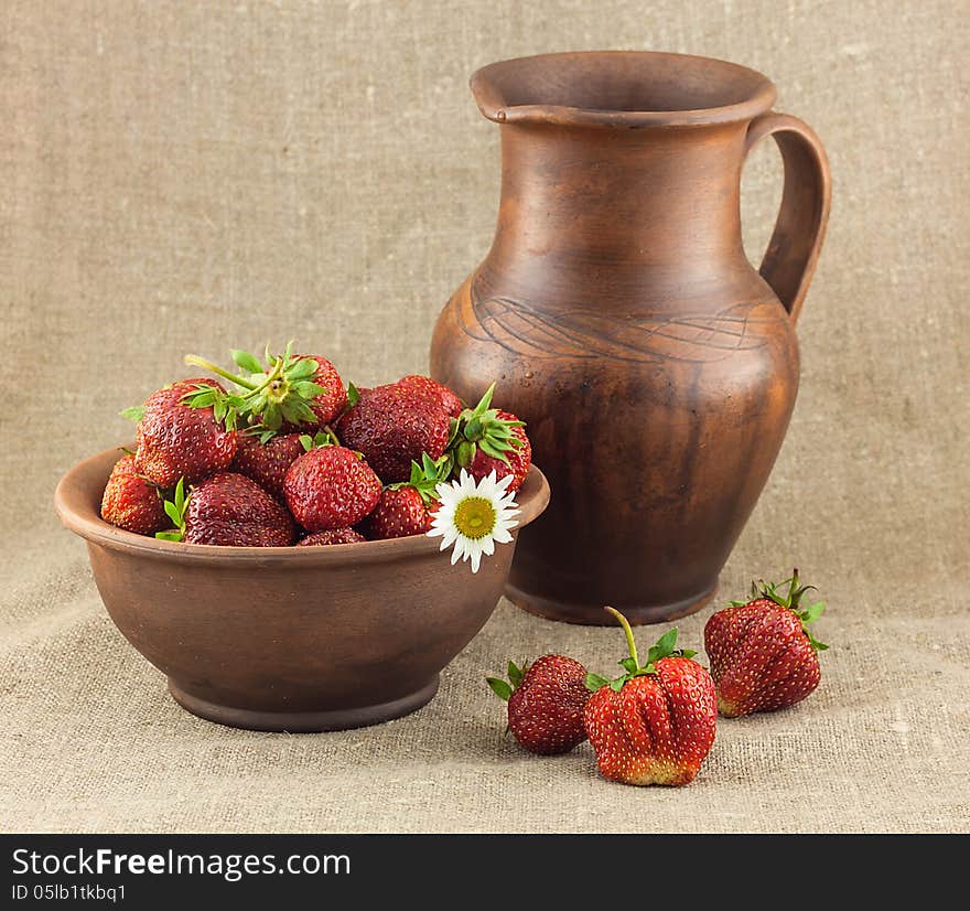 Rustic still life of strawberries in the clay pot