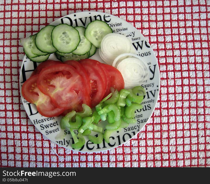 Raw uncooked Onions, cucumber, tomatoes, celery. On a plate. Raw uncooked Onions, cucumber, tomatoes, celery. On a plate.