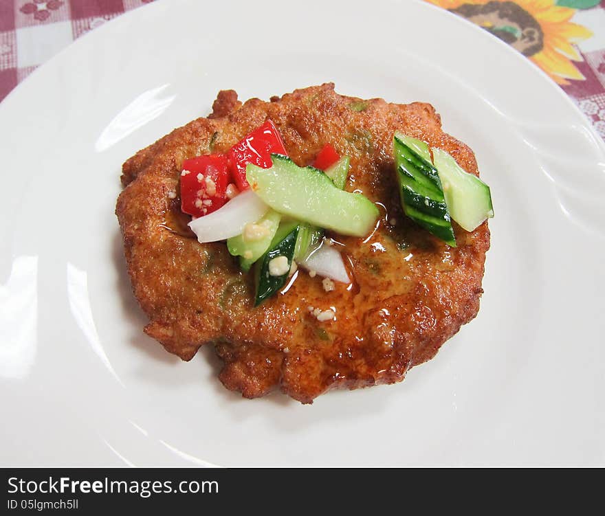 A single nugget with sweet sauce and vegetables served on a white plate.