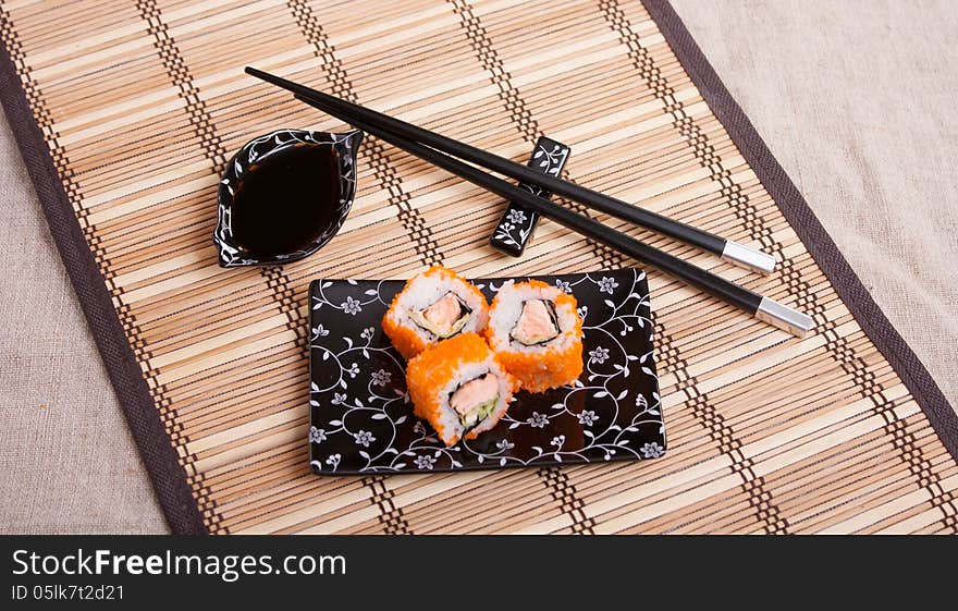 Japanese food - rolls with salmon on a wicker napkin with Japanese equipment