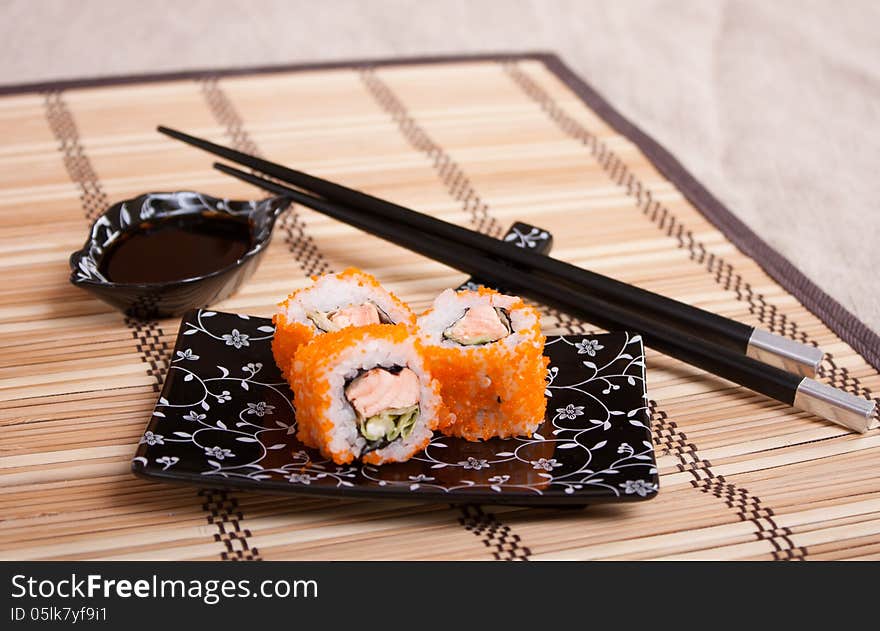 Japanese food - rolls with salmon and caviar on kappelana wicker napkin with Japanese equipment