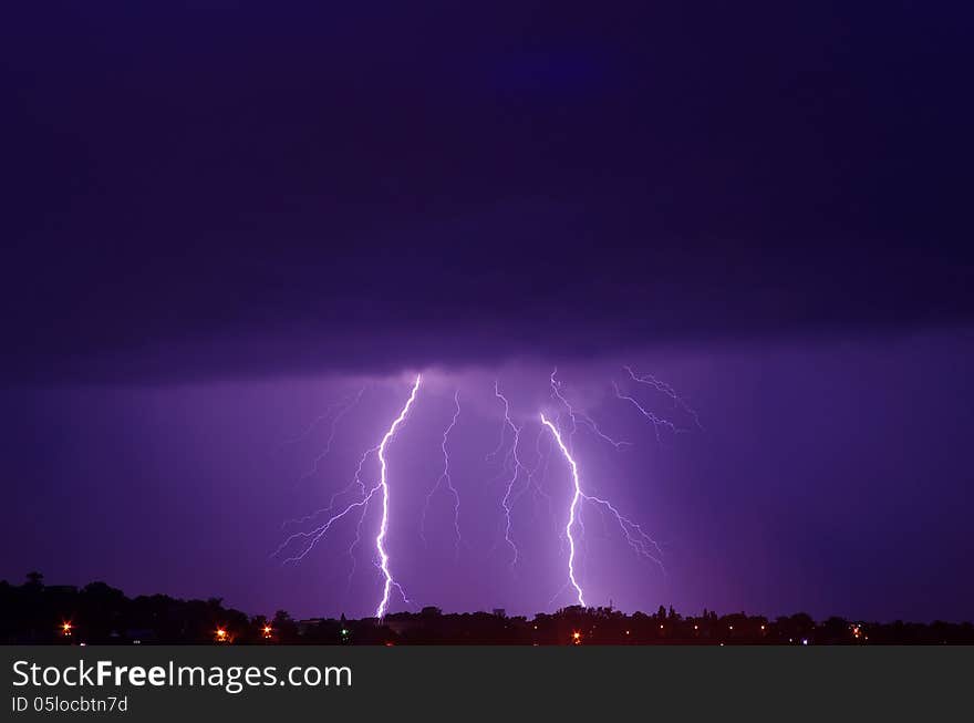 Lightning on the background of dark blue, purple clouds in the city