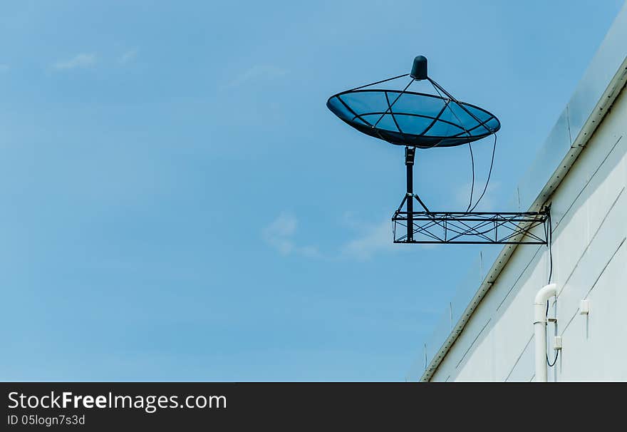 Black satellite dish on roof against blue sky