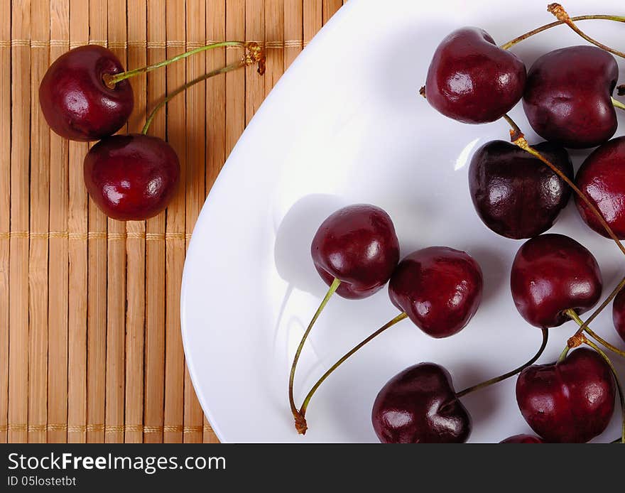 Sweet cherries in water drops on white plate