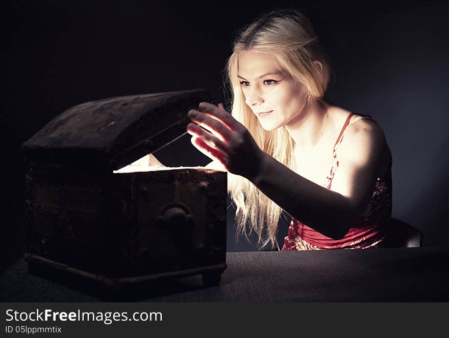 Young blond woman securing her treasure in a retro wooden chest. Young blond woman securing her treasure in a retro wooden chest