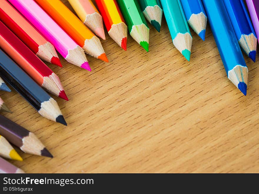 Line of colored pencils on wooden background