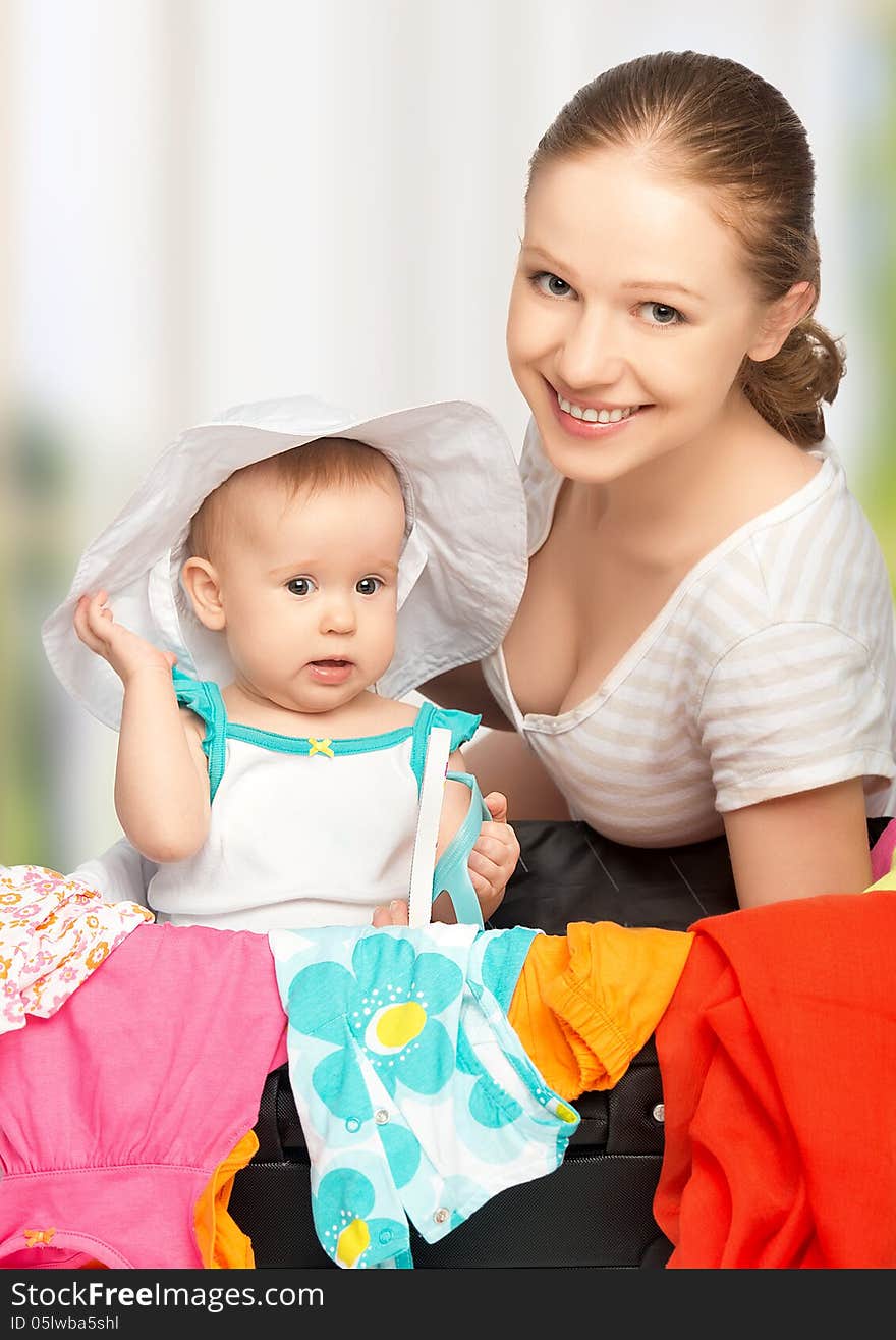 Mother and baby girl with suitcase baggage and clothes ready for traveling on vacation. Mother and baby girl with suitcase baggage and clothes ready for traveling on vacation