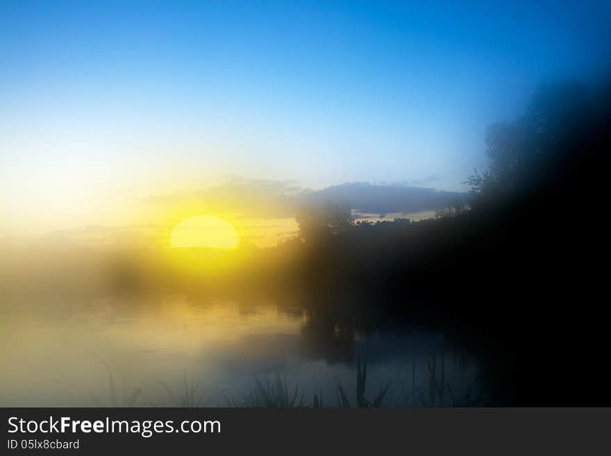 Mist lake and sun on blue sky dramatic illuminated morning