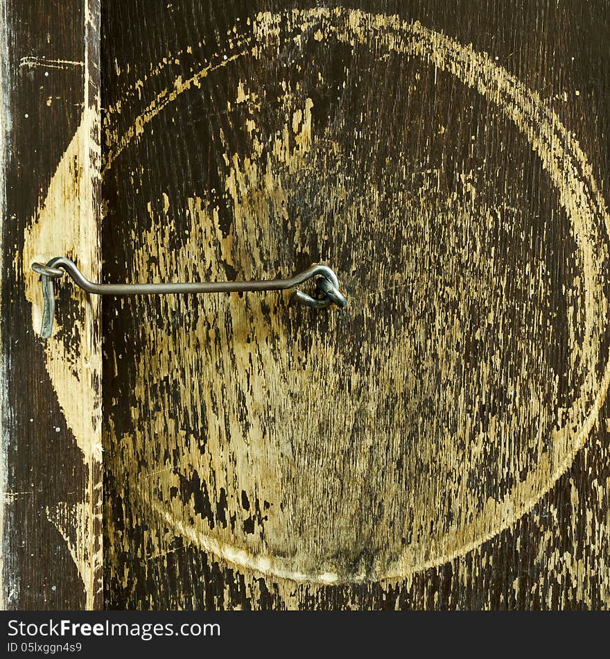 Old scraped wooden door with iron lock hangs. Old scraped wooden door with iron lock hangs.