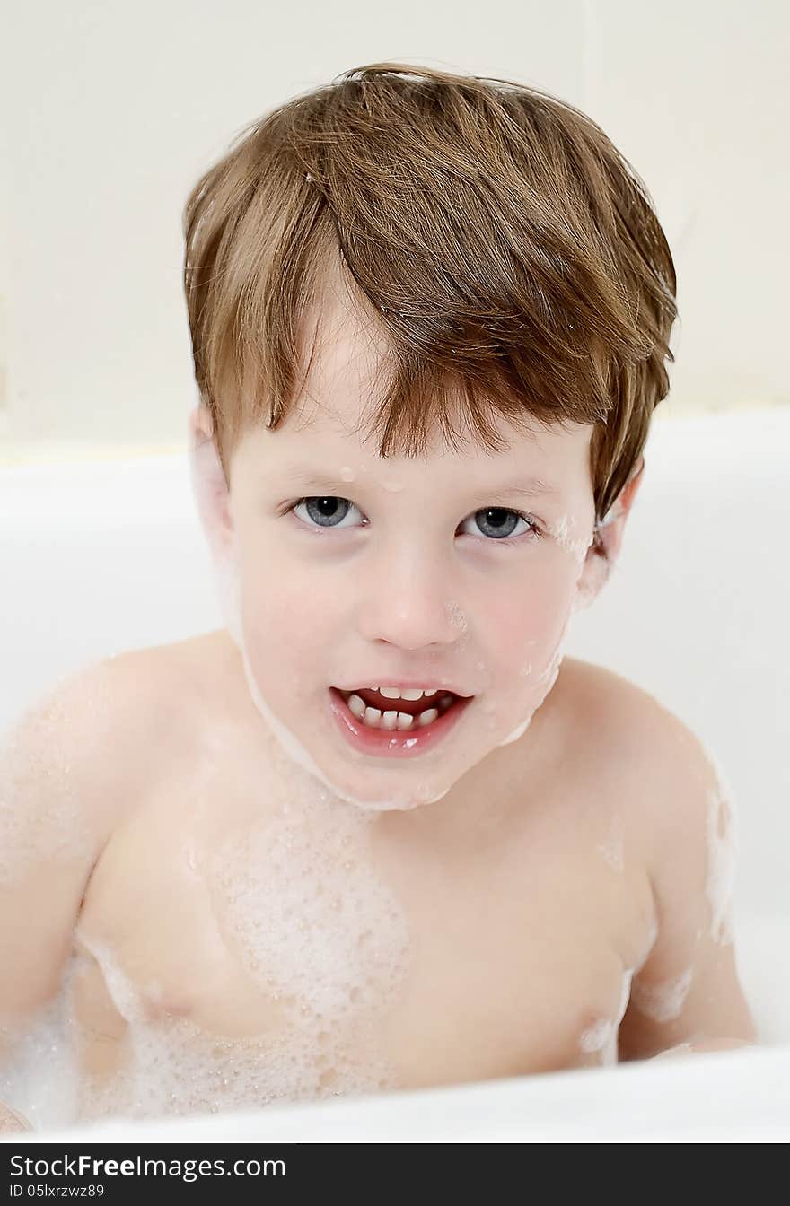 Cute three year old boy taking a bath with foam