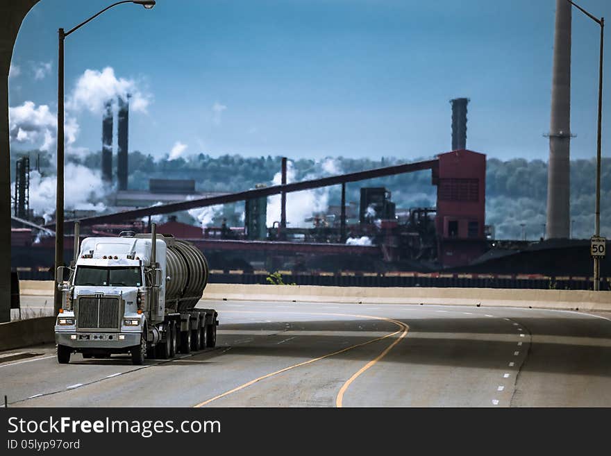 The heavy truck running from the industrial plant on the background. The heavy truck running from the industrial plant on the background