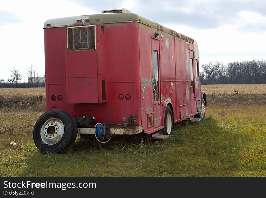 An old red and white camper trailer sitting in a field. An old red and white camper trailer sitting in a field