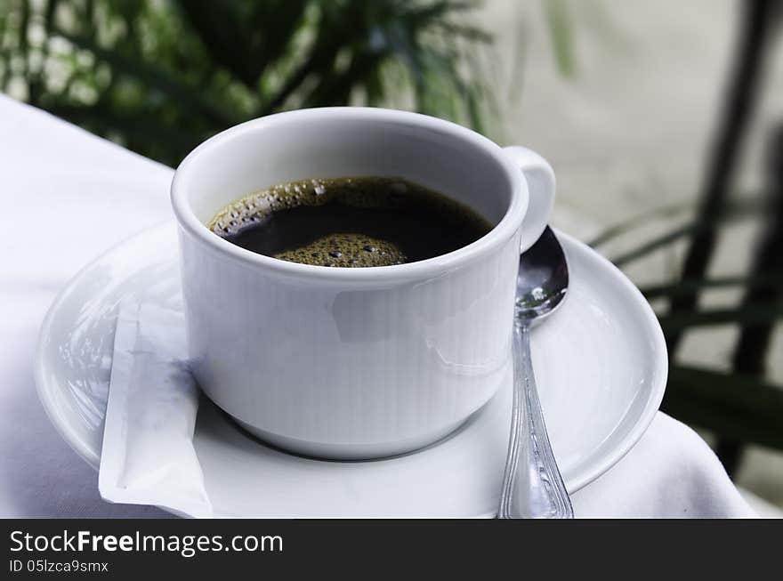 Black coffee with white table and tree background