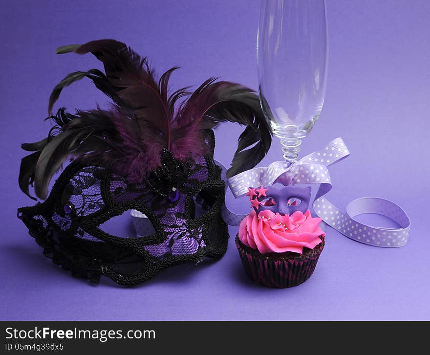 Pink and purple masquerade masks decorated party cupcake with pink frosting for teenage, birthday, New Years Eve, or wedding bridal shower party - with champagne glass and mask, vertical. Pink and purple masquerade masks decorated party cupcake with pink frosting for teenage, birthday, New Years Eve, or wedding bridal shower party - with champagne glass and mask, vertical.