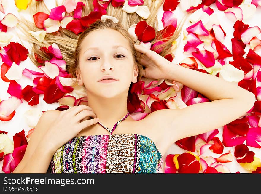 Young girl lies in the petals of roses