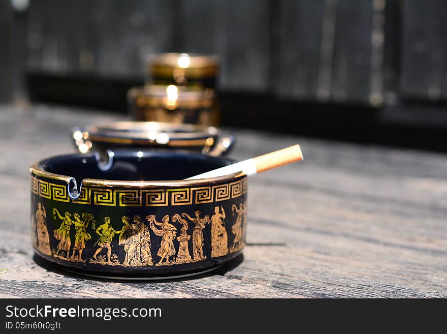 Cigarette in ashtray with Greek motifs. Cigarette in ashtray with Greek motifs