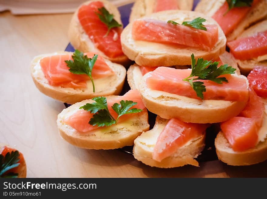 Sandwiches with smoked salmon and arugula on a black plate and wooden board