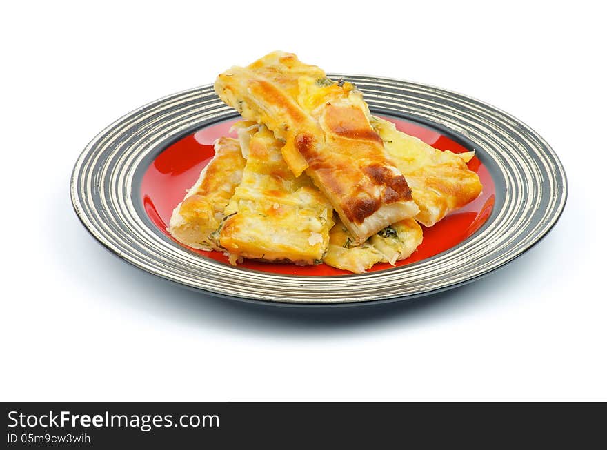 Slices of Cheese and Greens Puff Pastry Pie on Red Striped Plate  on white background. Slices of Cheese and Greens Puff Pastry Pie on Red Striped Plate  on white background