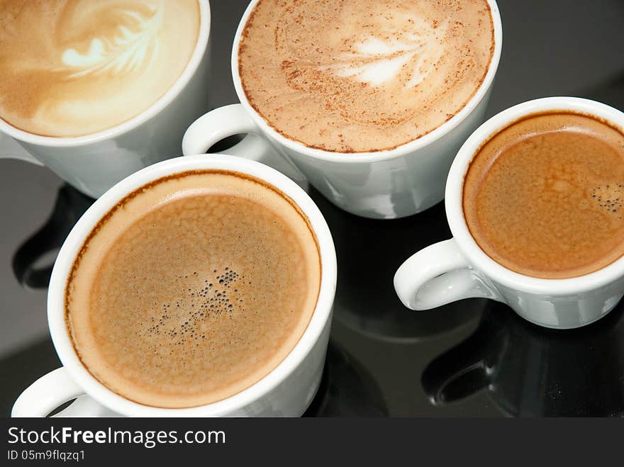 Four white coffe cups on the black background