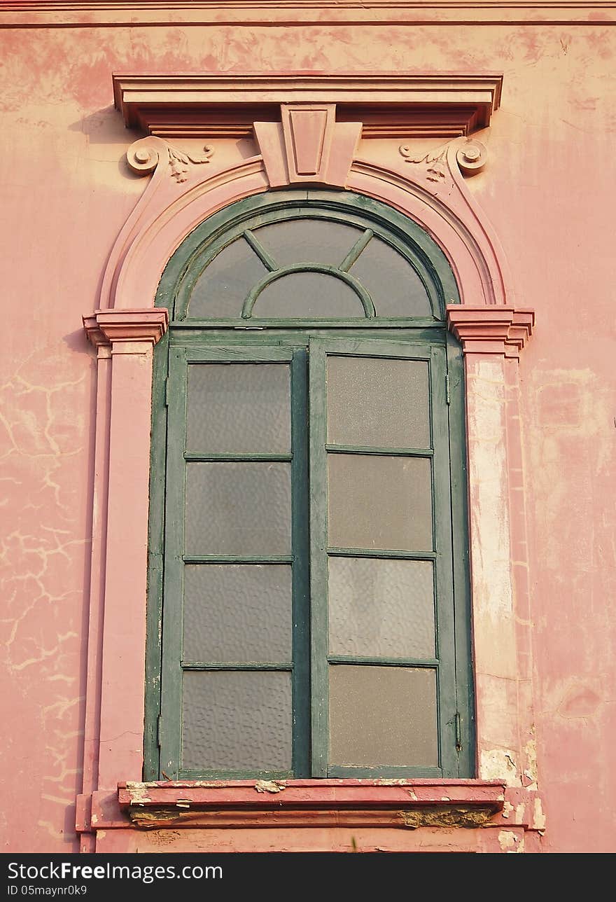 Ancient green glass window of old pink building. Ancient green glass window of old pink building