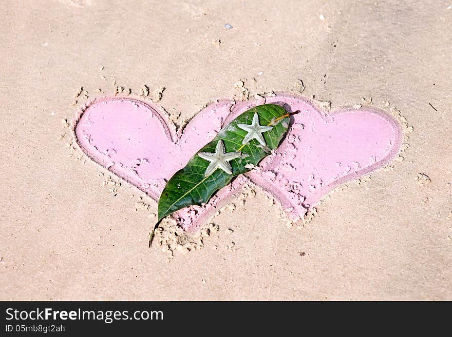 Still life with two drawn hearts and starfishes on wet sand