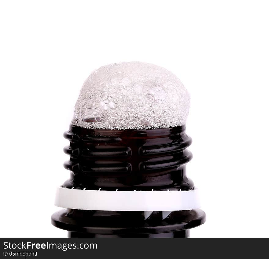 Froth cap of open beer bottle close-up on the white background