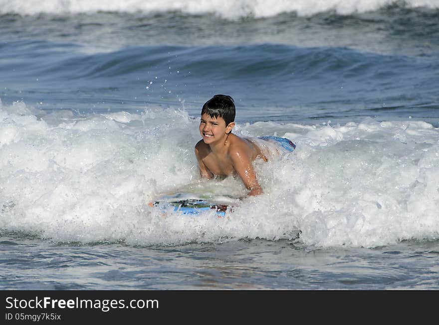 A boy with his tablet to surf on blue waves of the Mediterranean Sea. A boy with his tablet to surf on blue waves of the Mediterranean Sea