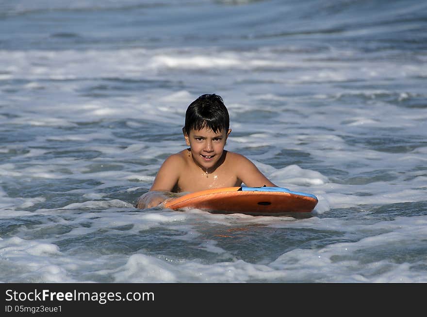 A boy with his tablet to surf on blue waves of the Mediterranean Sea. A boy with his tablet to surf on blue waves of the Mediterranean Sea