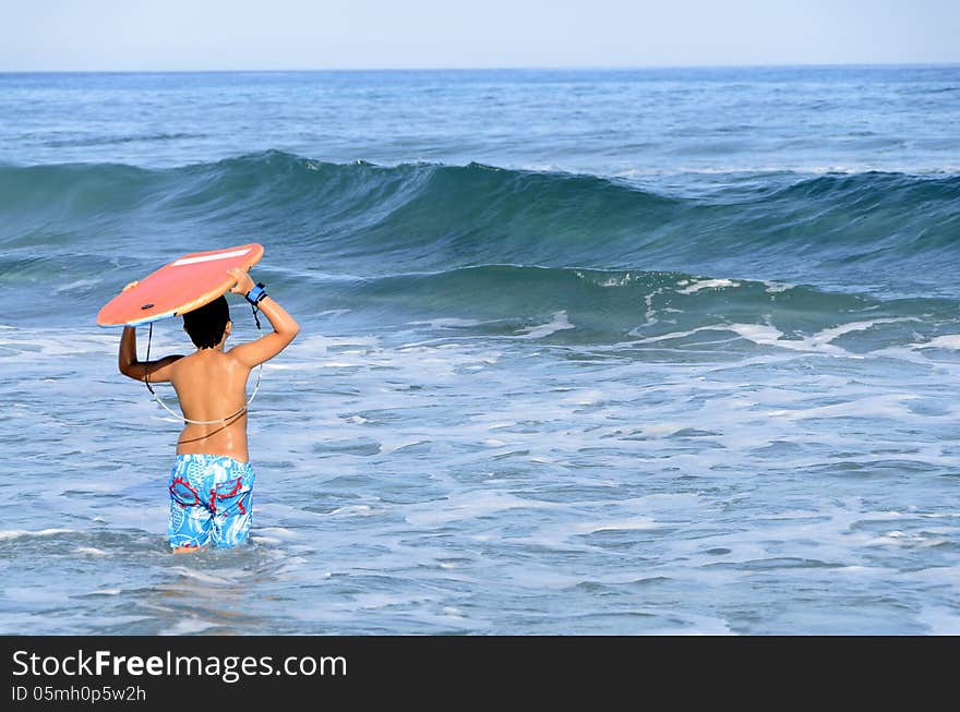 A boy with his tablet to surf on blue waves of the Mediterranean Sea. A boy with his tablet to surf on blue waves of the Mediterranean Sea