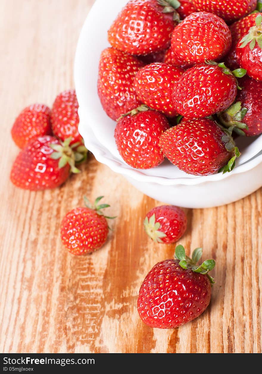 Dish of ripe strawberries on a wooden table. Dish of ripe strawberries on a wooden table