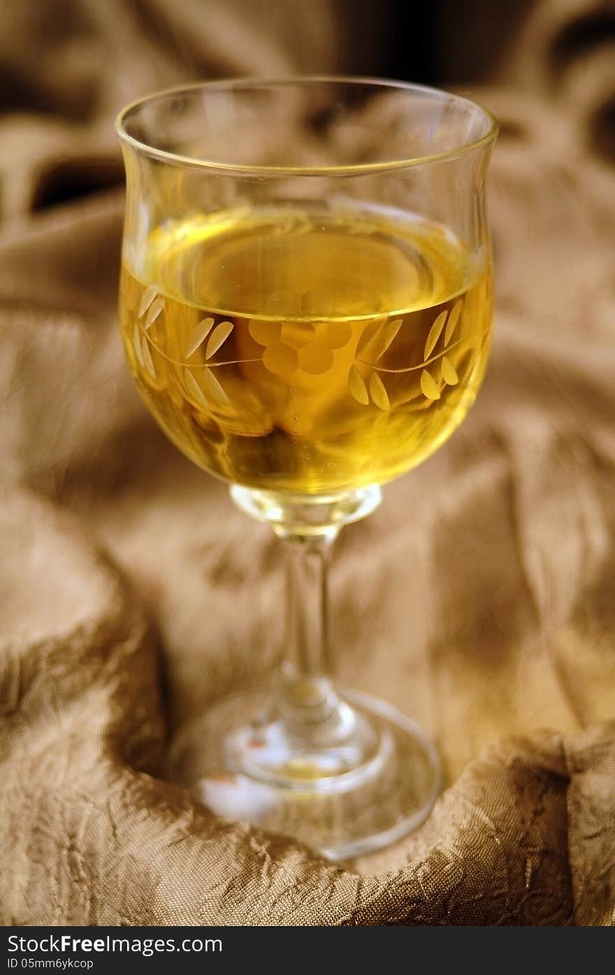 White wine in crystal glass and golden backcloth