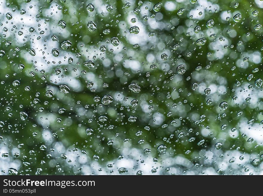 Water drop on clear glass with green in background