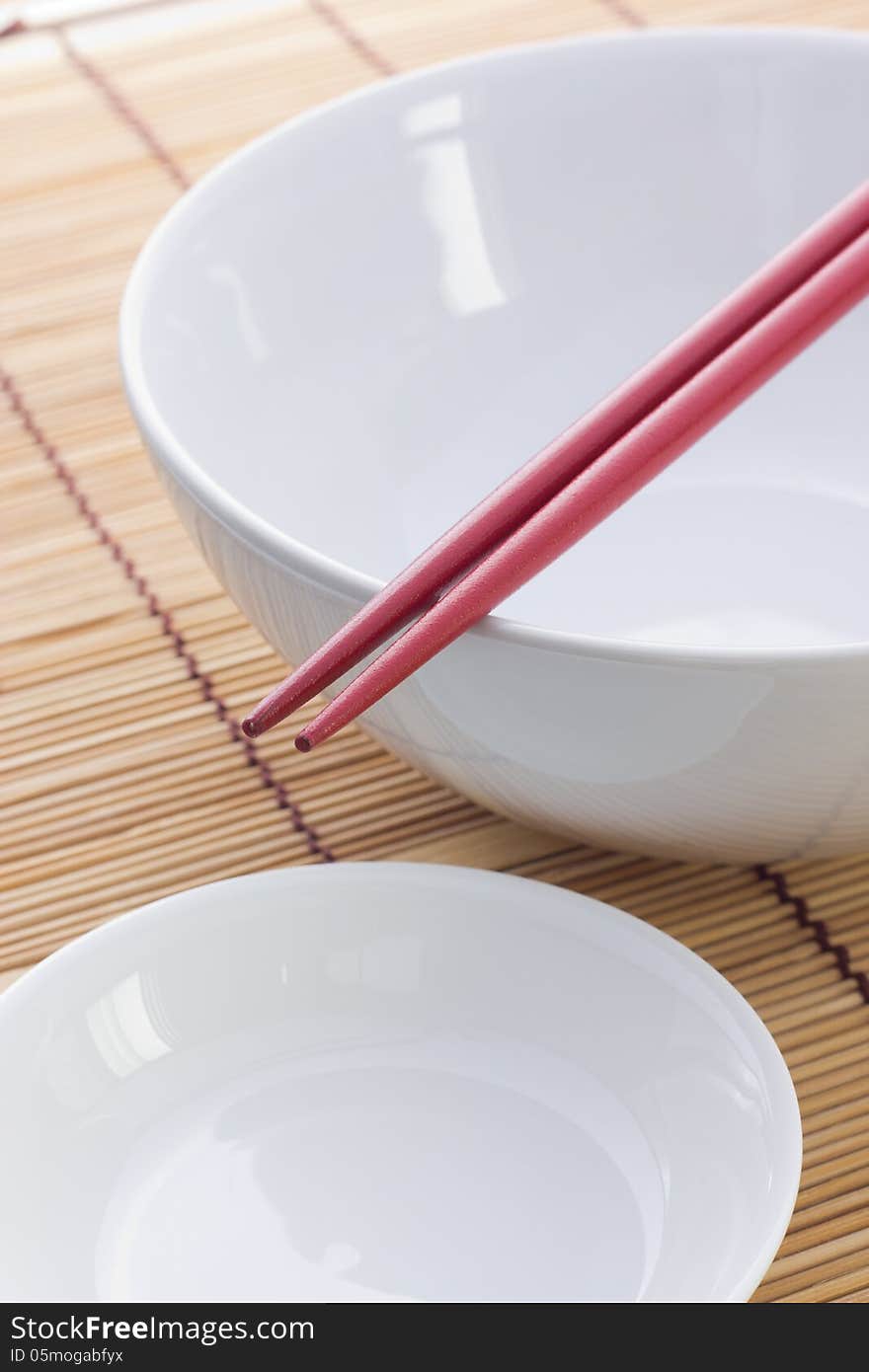 Two chopsticks next to and white bowl