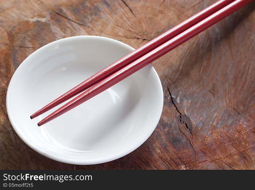 Two chopsticks next to a red and white bowl