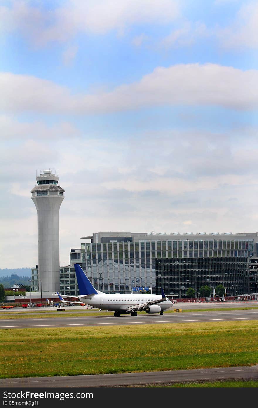 The Portland air traffic control tower sits beside a large parking garage with a plane sitting ready for take off. Turbulent skies. The Portland air traffic control tower sits beside a large parking garage with a plane sitting ready for take off. Turbulent skies.