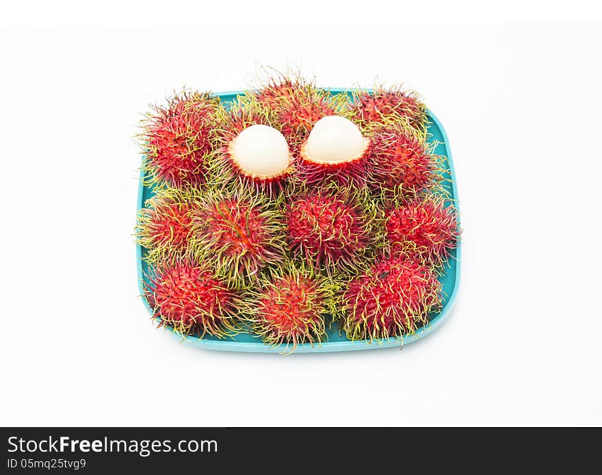 Rambutan in green dish isolated on white background.