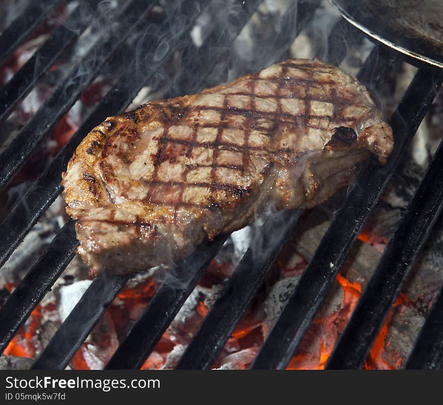 Beef steak cooking on an open flame grill