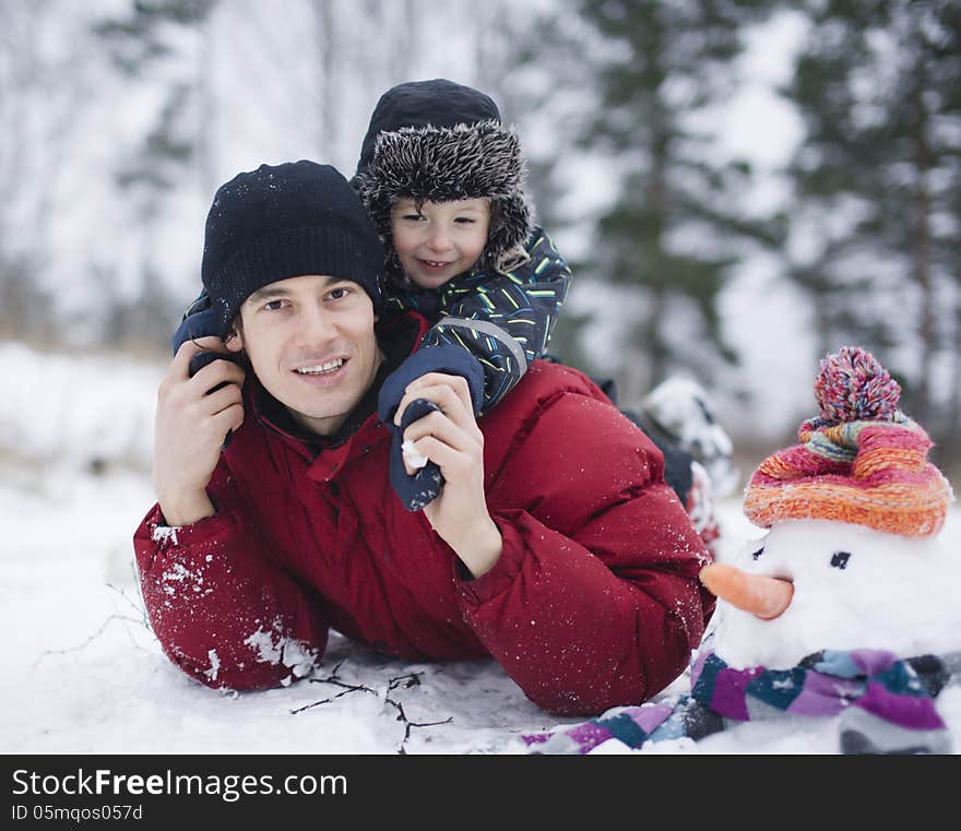 Happy father with his son outside with snowman