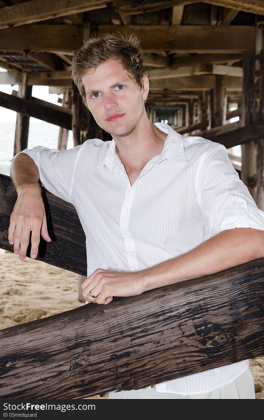 Good looking young man at the beach under the pier. Good looking young man at the beach under the pier.