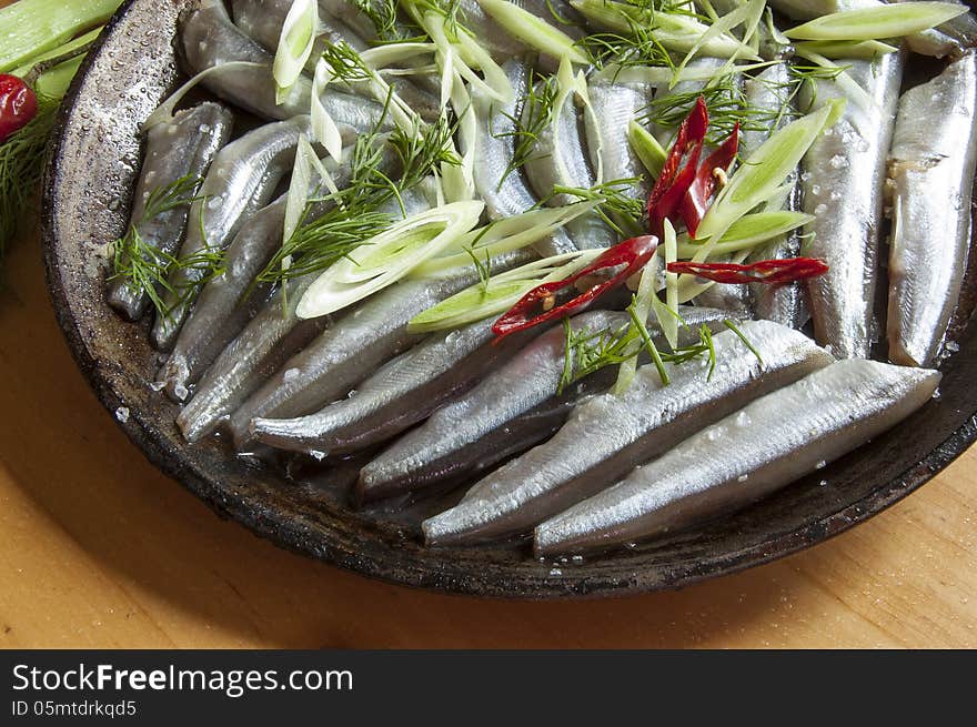 The process of cooking fish. Fresh fish on an old frying pan. Horizontal image, macro. The process of cooking fish. Fresh fish on an old frying pan. Horizontal image, macro.