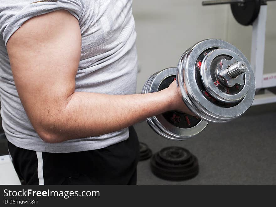 The guy lifts a dumbbell, is photographed by a close up