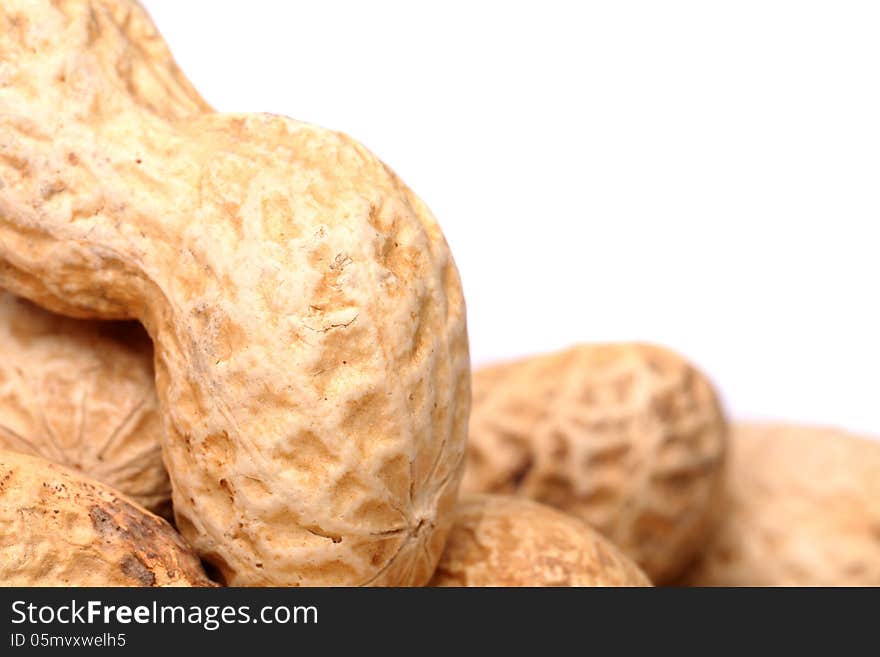 Roasted in-shell peanuts close-up are located left on the white background. Roasted in-shell peanuts close-up are located left on the white background.