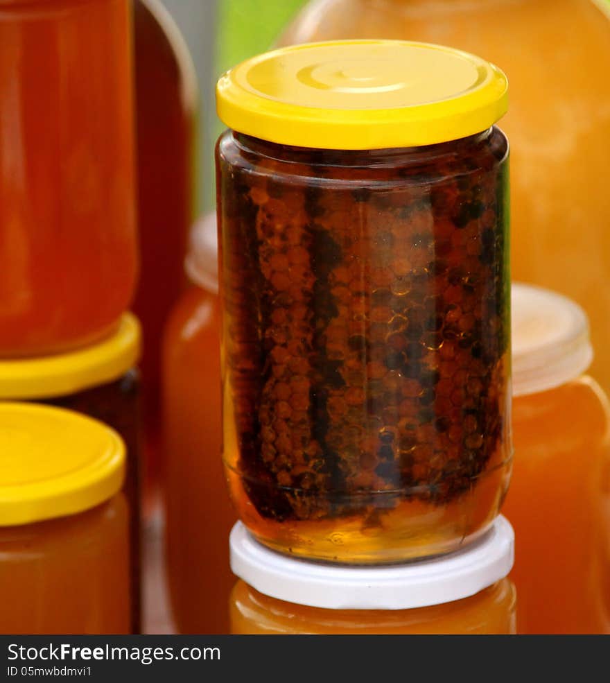 A honeycomb and a honey in a glass jar