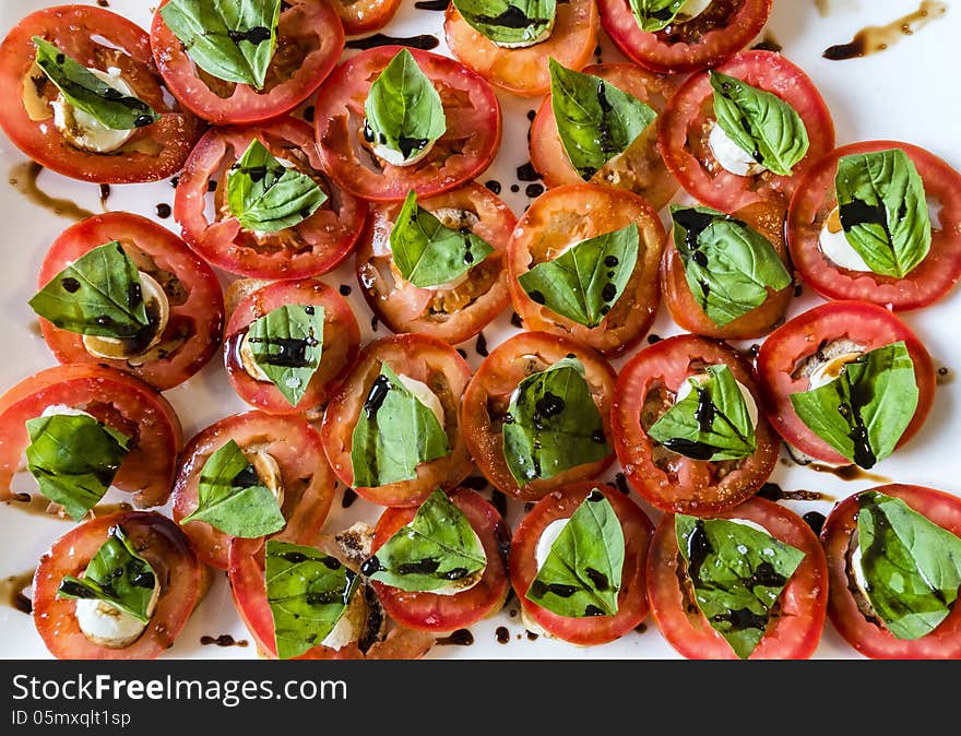 Tomatoes basil craker and balsamic vinegar on a white plate. Tomatoes basil craker and balsamic vinegar on a white plate