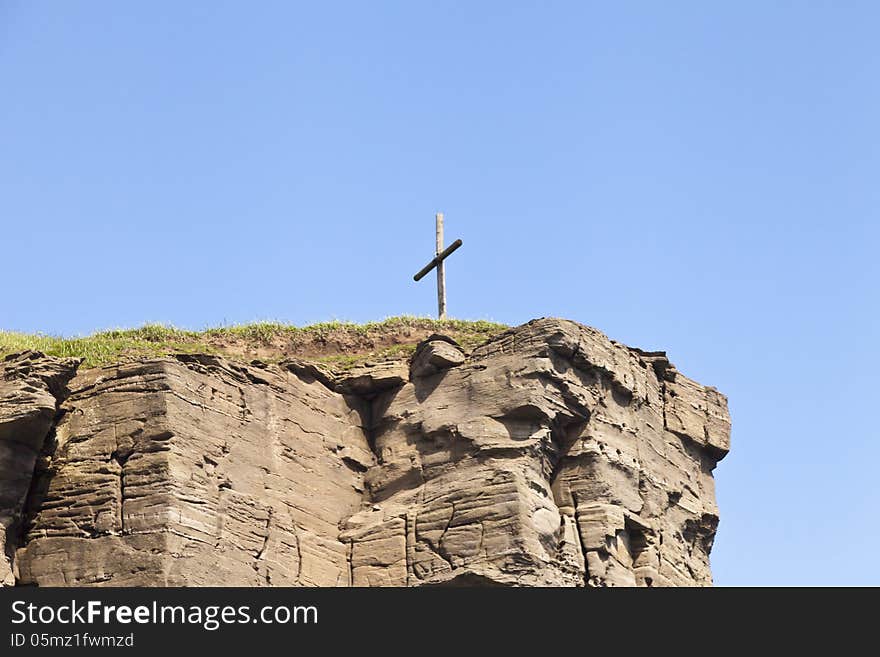 The cross on the rock over the sea meets floating ships