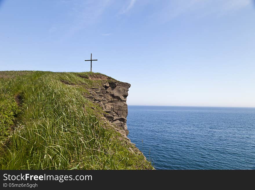 The cross on the rock over the sea meets floating ships